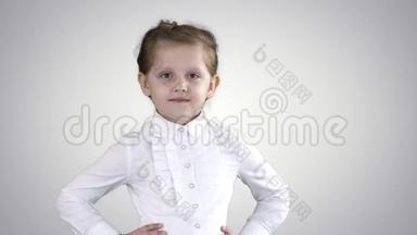 可爱的小女孩穿着白色连衣裙，在渐变背景下的相机上摆姿势。